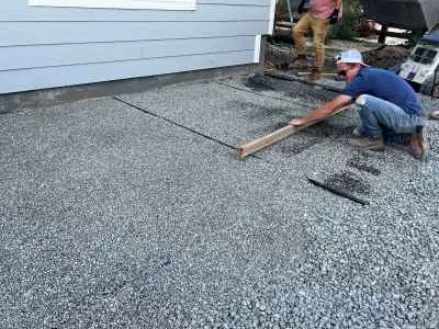 Screeding a compacted angular-gravel base with string lines