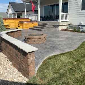 Custom-designed stamped concrete patio with integrated seating wall and fire pit in a Castle Pines home.