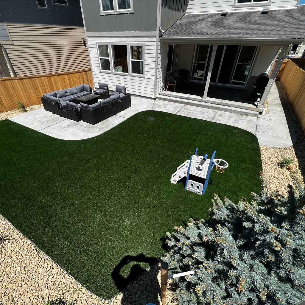A bird's-eye view of a Castle Pines backyard showcasing a perfect blend of artificial turf and concrete patio.