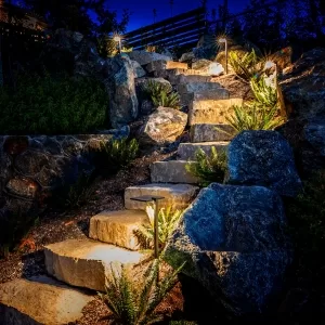 Outdoor step lighting illuminating a rock pathway at night.