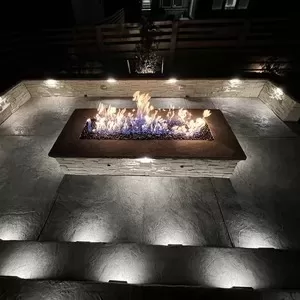 A modern fire pit with built-in seating, surrounded by soft outdoor lighting.